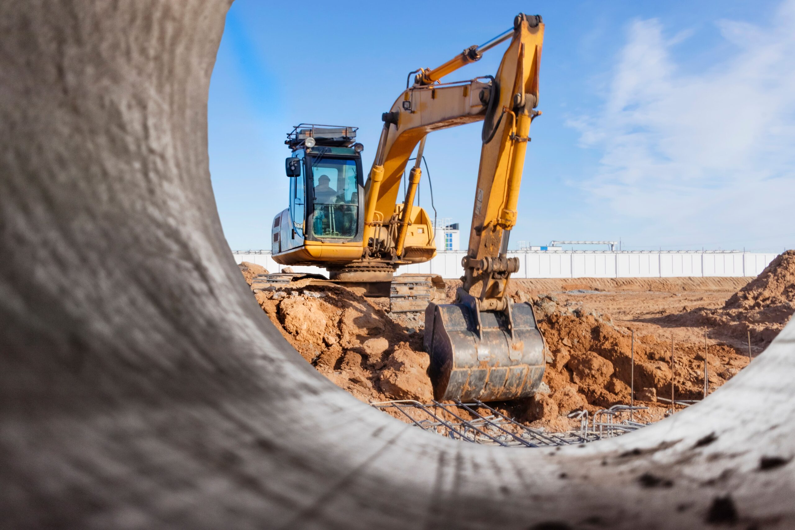 View of a digger through a pipe on work site